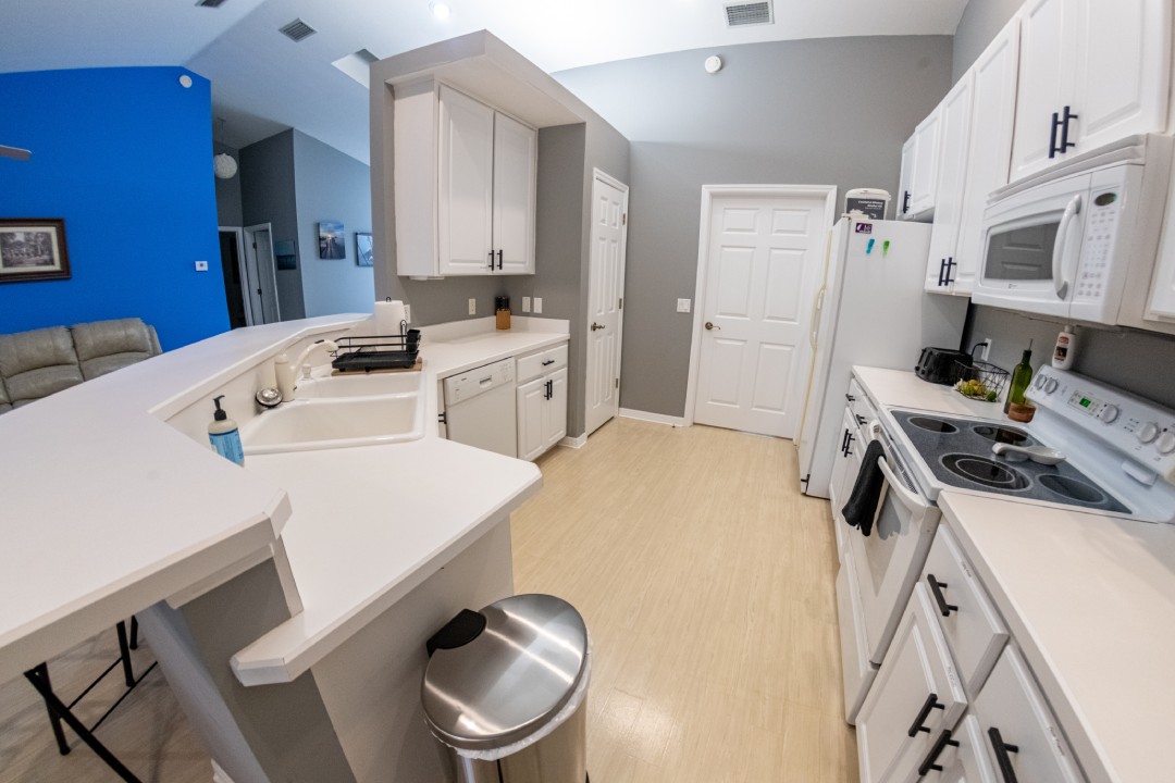 Modern and sleek kitchen design at Hideout Heights Vacation Rental with white cabinetry and appliances for a comfortable stay.