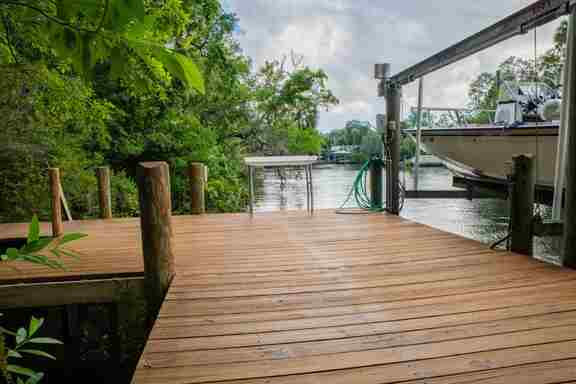 Wooden dock at Hideout Heights with a fish cleaning table and a boat lift, right by the water.